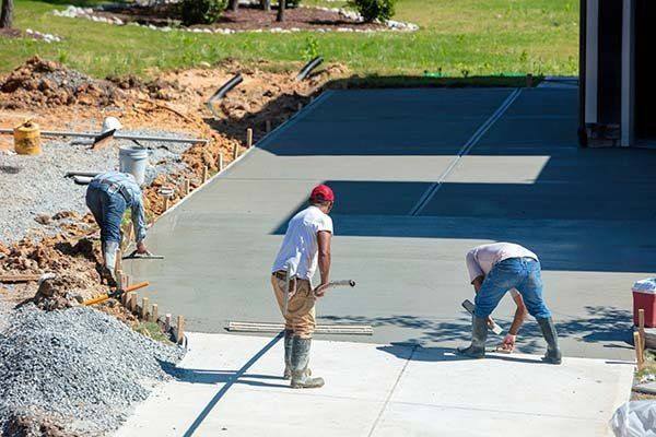 Crew placing and finishing a new concrete driveway