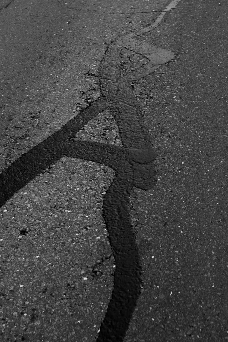 Asphalt surface with long cracks sealed with black rubberized crack sealant