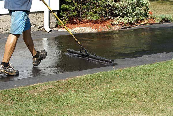Worker spreading driveway sealer with a squeegee