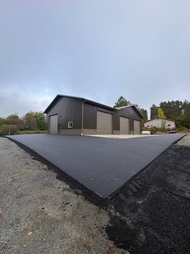 Newly paved asphalt apron in front of a large garage building