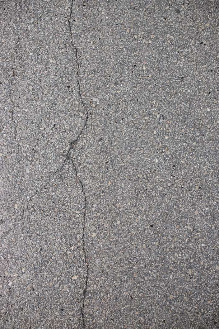 A single long open crack running through gray asphalt