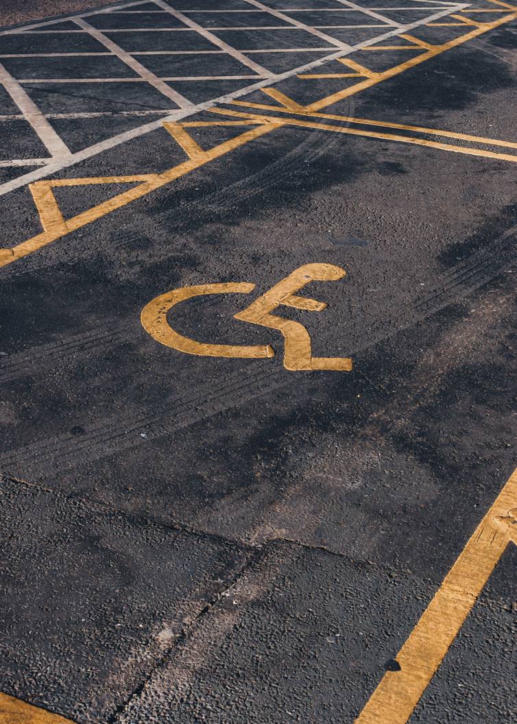 Yellow parking stall lines and an accessible parking symbol painted on dark asphalt