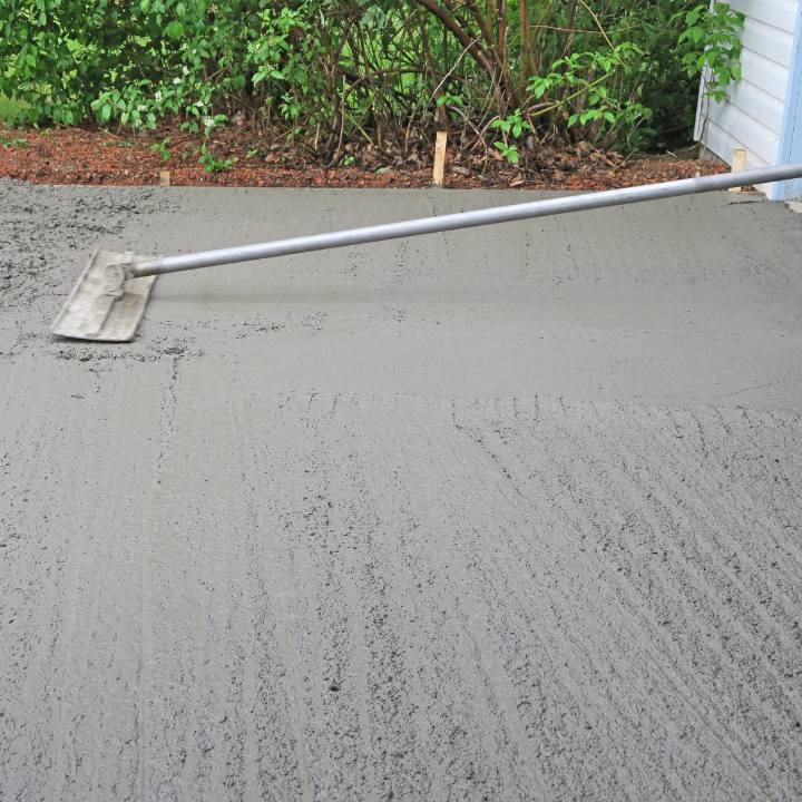 Fresh concrete being leveled with a long-handled finishing tool